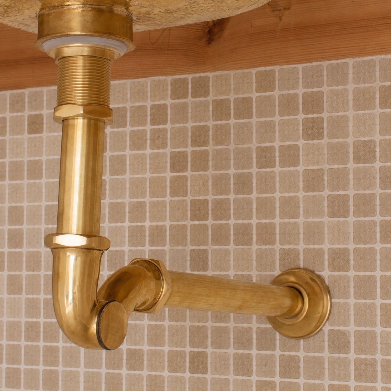 Solid unlacquered brass bathroom sink P-trap and push-button pop-up drain assembly with matching exposed plumbing components.