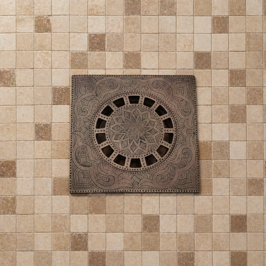 Handmade Moroccan copper shower drain with engraved square floor drain cover installed on beige mosaic bathroom tiles