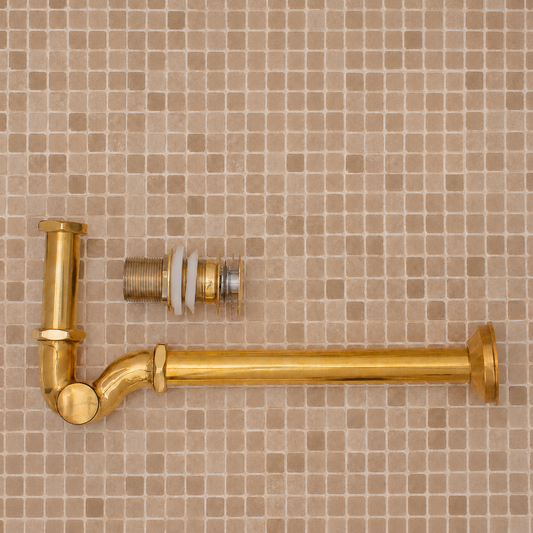 Solid unlacquered brass bathroom sink P-trap and push-button pop-up drain assembly with matching exposed plumbing components.