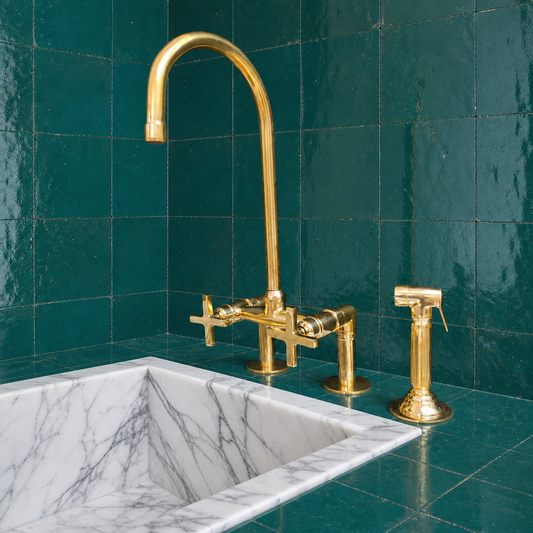 Unlacquered brass bridge kitchen faucet with cross handles, tall gooseneck spout and handheld side sprayer